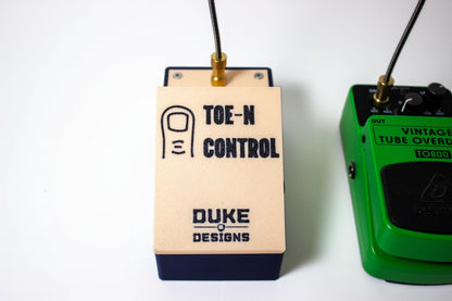 A top-view of a mechanical expression guitar pedal with the words Toe-N control and Duke Designs on its pedal top