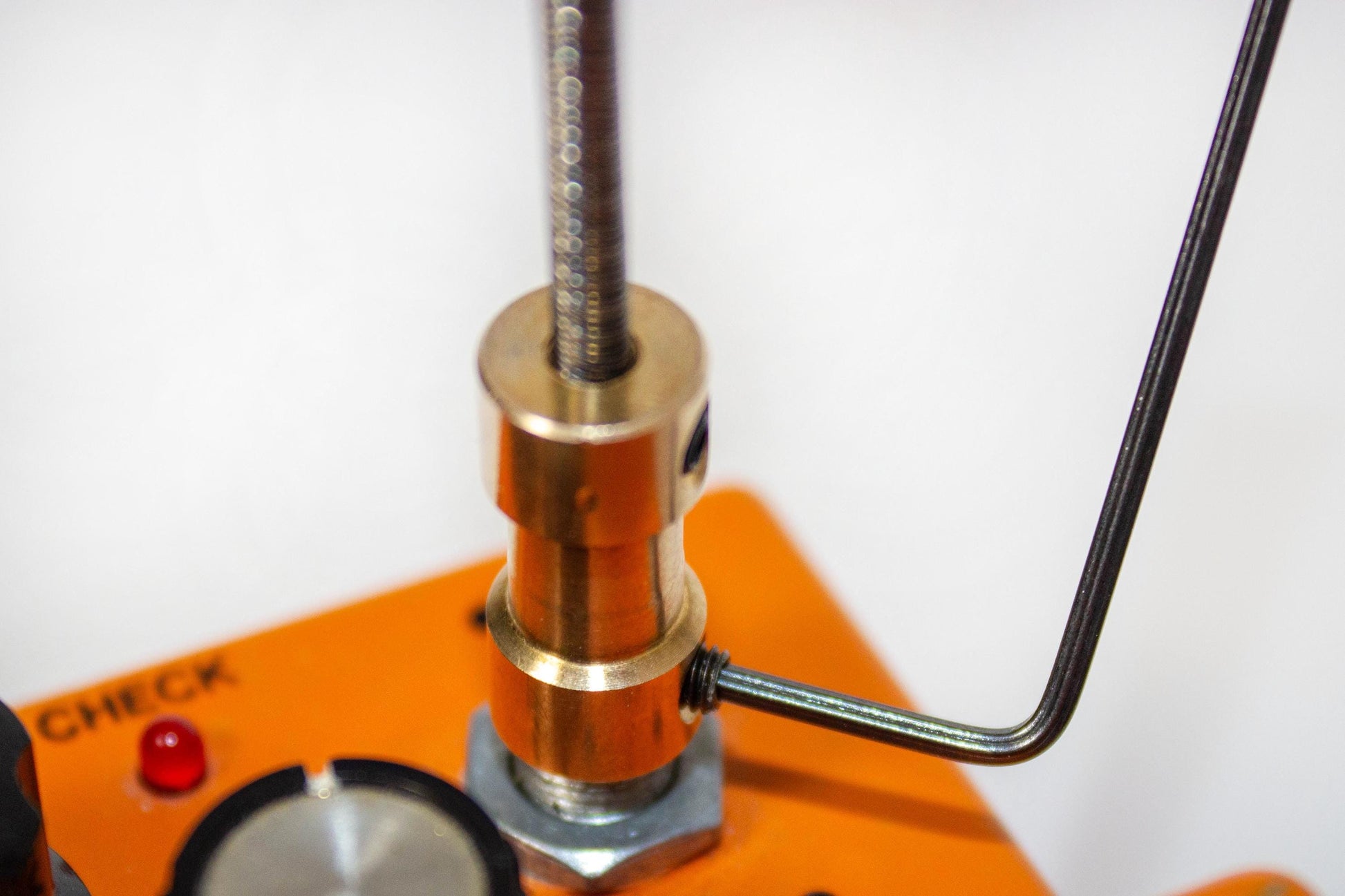 A brass colored adaptor is shown attaching the guitar pedals flexible shaft to another guitar pedal&#39;s knob